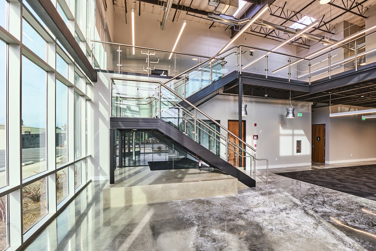Modern office lobby with stairway and glass walls at 9615 Norwalk Blvd